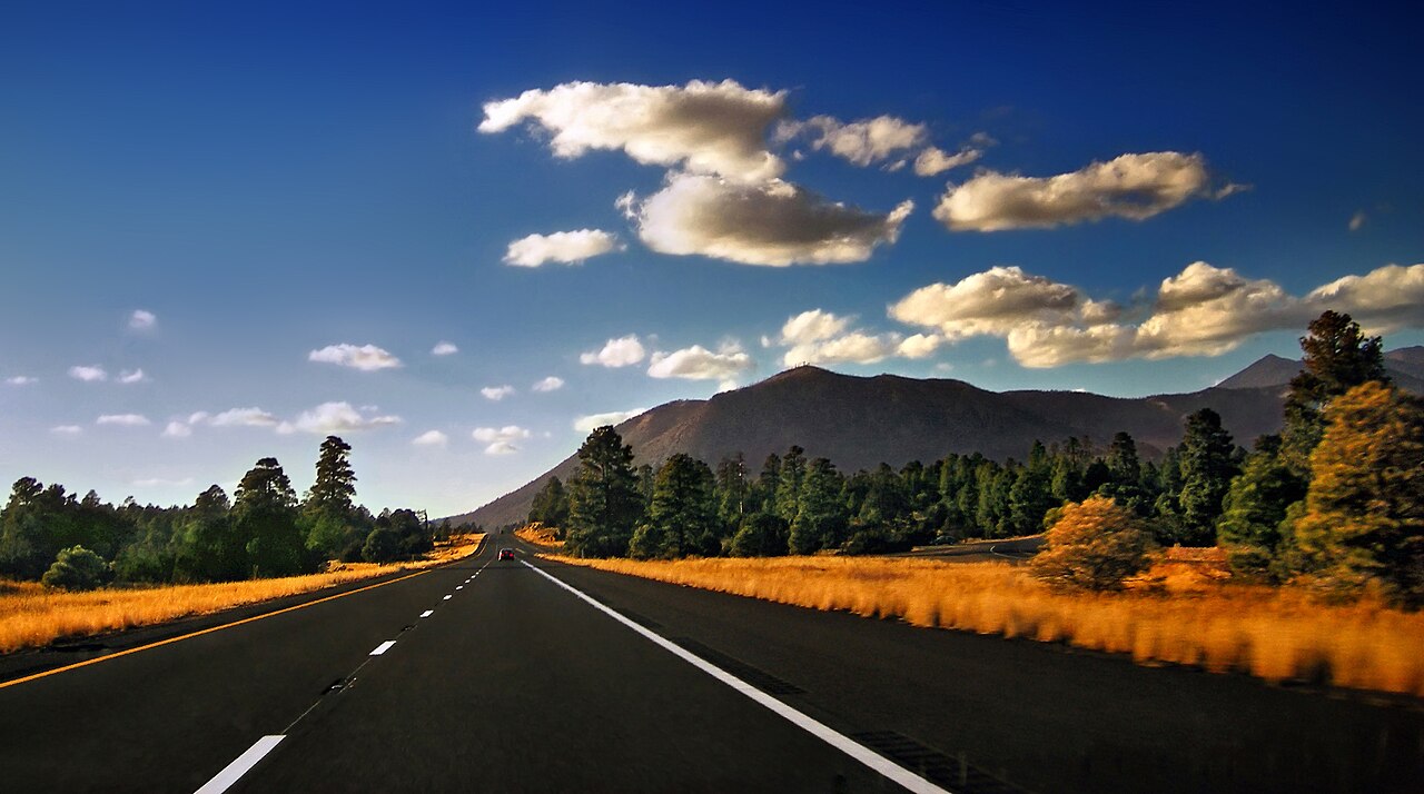 Interstate 40 westbound near Flagstaff, Arizona, where the highway climbs through the high country toward the San Francisco Peaks.