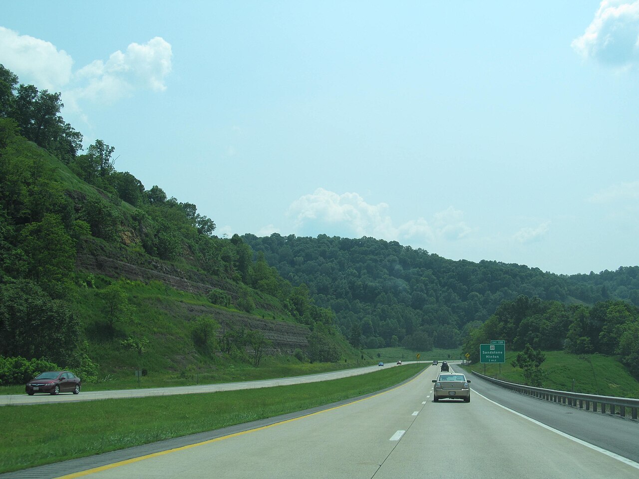 Interstate 64 sweeps through a rock cut and descends the forested ridge of Sandstone Mountain toward the Sandstone and Hinton exit in Summers County, West Virginia.