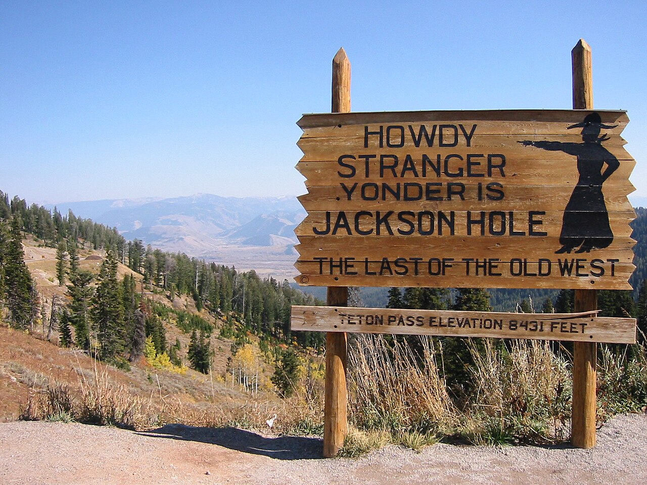 The roadside summit sign on Wyoming Highway 22 at Teton Pass reading 'Yonder Lies Jackson Hole' with the 8431-ft elevation marker.